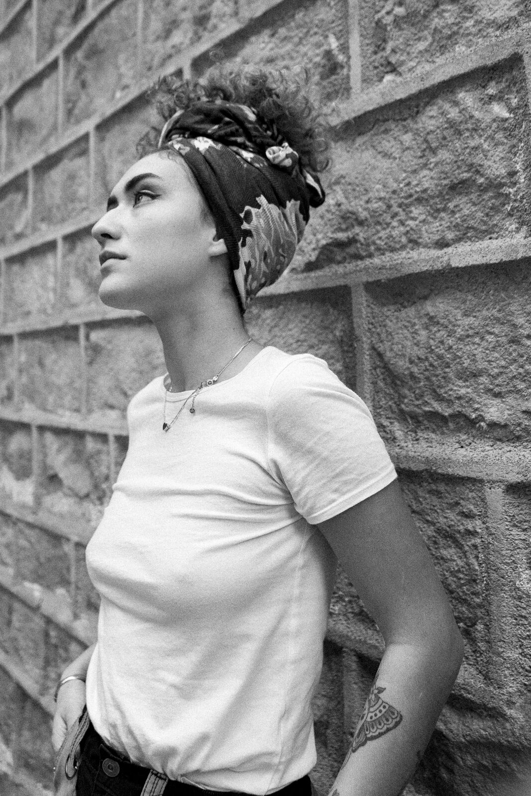 Retrato de perfil contra muro de ladrillo, blanco y negro