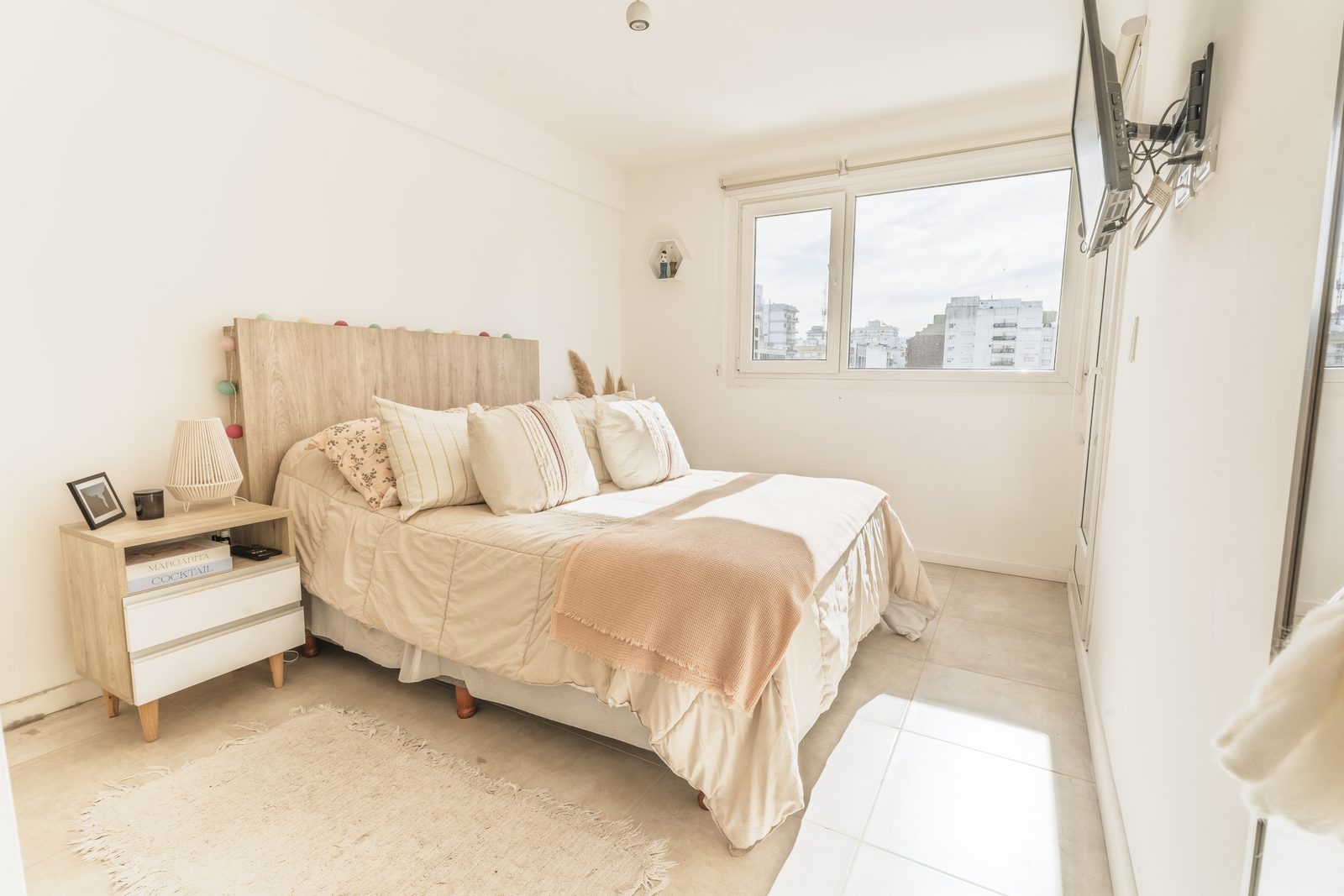 Dormitorio en paleta clara con ventanal y vista urbana