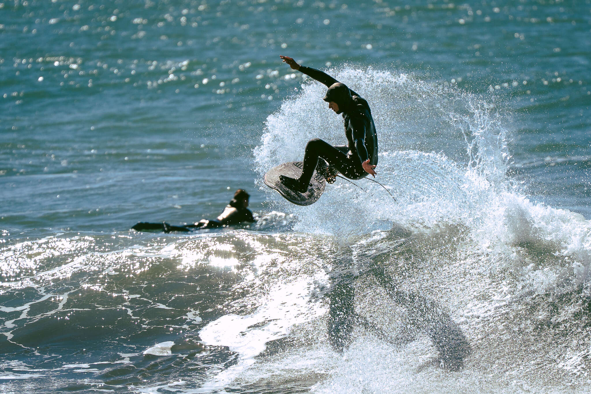 Surfista levantando espuma en la cresta de una ola